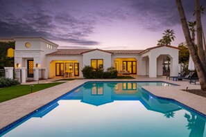 Una casa moderna con piscina, patio y césped bien cuidado.