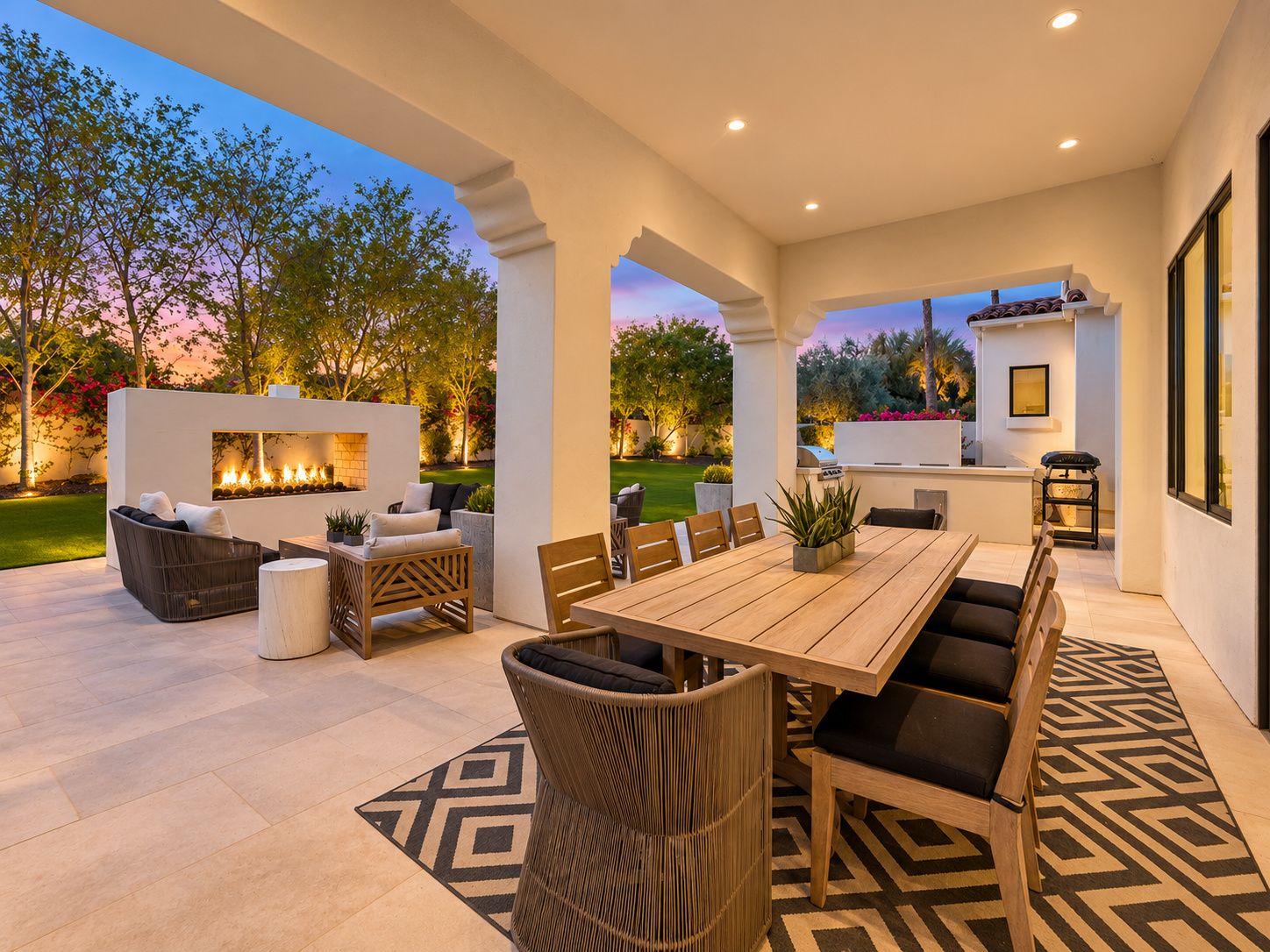 An outdoor patio with a dining table, chairs, and a fire feature.