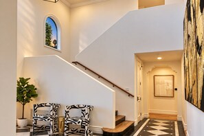 A staircase with a wooden handrail, a potted plant, and two zebra-patterned chairs.