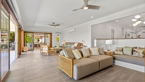 A spacious living area with a large sofa, a wooden coffee table, and a dining table with chairs. There are ceiling fans and recessed lighting. - Hale Oahu Lic.#1990/NUC-1777/1778 BEACHFRONT KAILUA LUXURY (Kailua)
