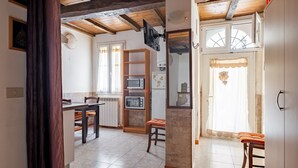 A kitchen with a dining area, wooden beams, a TV, and a refrigerator.