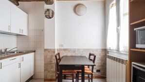 A kitchen with white cabinets, a wooden table, and a stone wall.