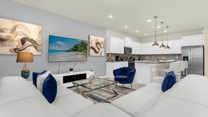 A modern living room with a glass coffee table, white sofas, and a blue armchair. - Spectacular Resort Themed Luxury! LED Games Room - Prime Disney! (Davenport)