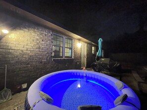 An outdoor swimming pool with a brick wall and a door in the background.