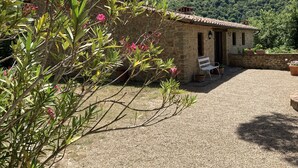 Un bâtiment en pierre avec un toit en tuiles, un banc et une cour recouverte de gravier.