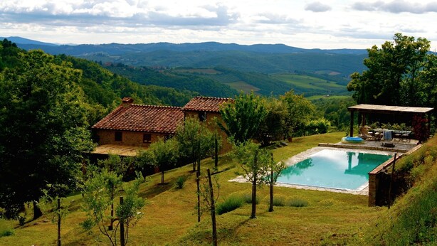 Une villa avec piscine, entourée d’une végétation luxuriante et avec des montagnes en toile de fond.