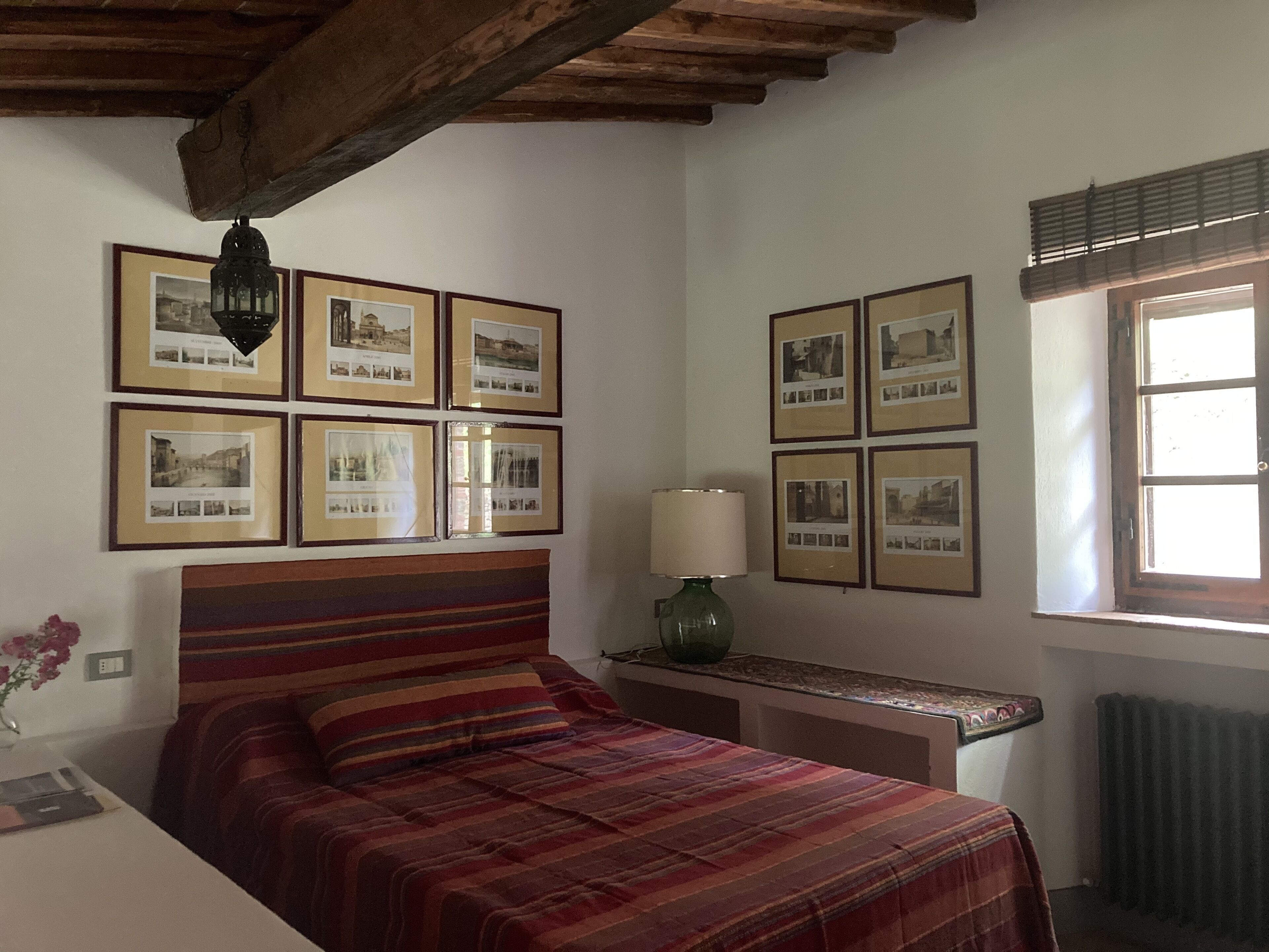 A bedroom with a bed, a nightstand, a lamp, and framed pictures on the wall.