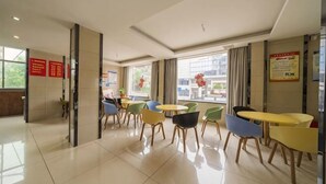 Un hall d’hôtel comprenant un comptoir d’accueil, plusieurs espaces de détente avec des fauteuils et des tables, et de grandes fenêtres donnant sur l’extérieur.