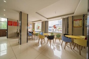Een hotel lobby met een receptiebalie, meerdere zithoeken met stoelen en tafels, en grote ramen met uitzicht.