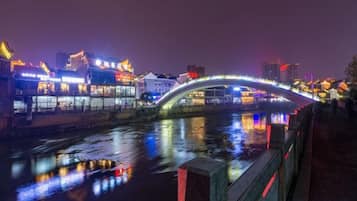 A nighttime view of a river with a bridge, illuminated buildings, and a reflection on the water.