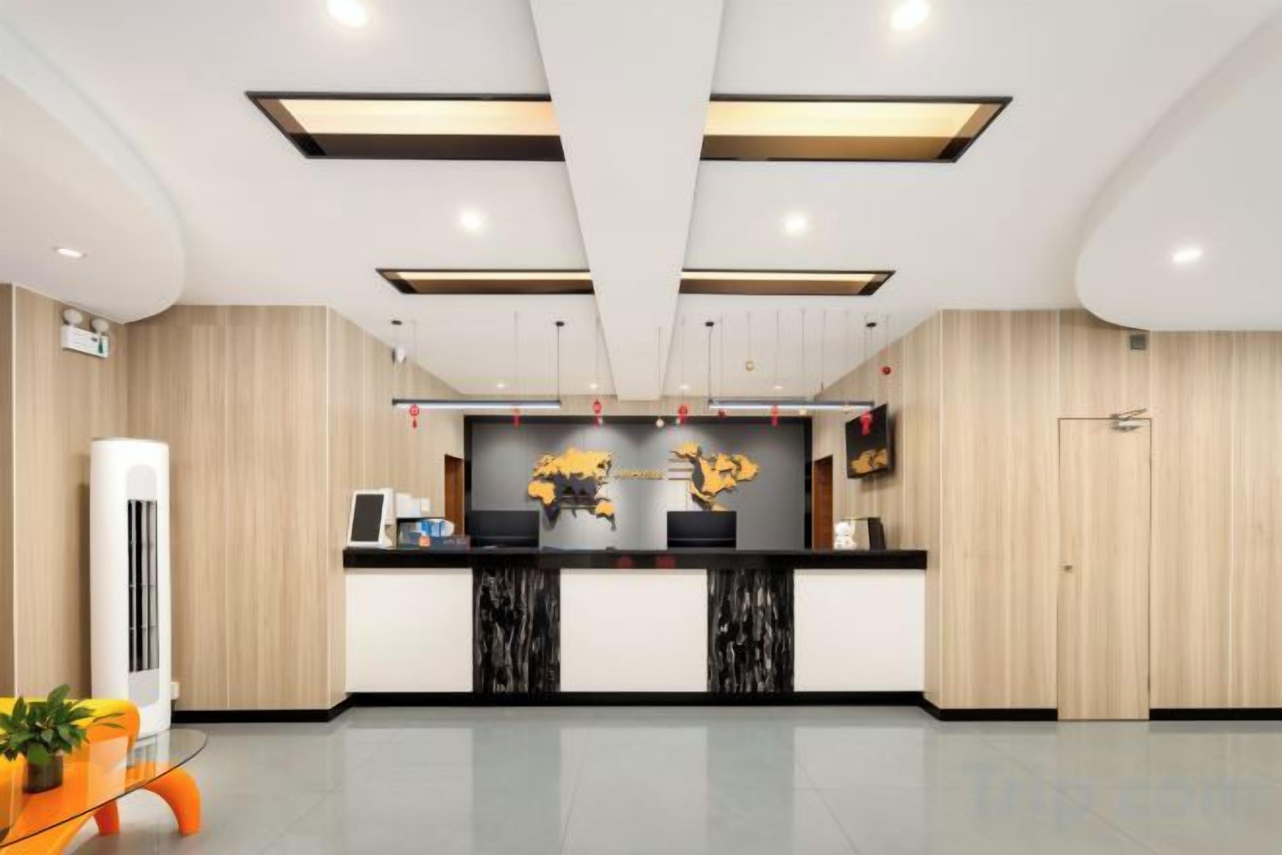 A reception area with a reception desk, two black marble counters, a wall-mounted display, and a potted plant.