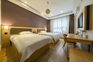 Quarto de hotel com duas camas, uma escrivaninha, uma cadeira, televisão e janela com cortinas.