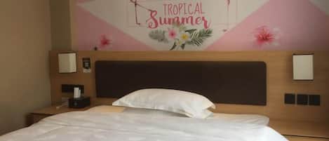 A hotel room with a bed, a headboard, two bedside tables, and a wall mural depicting flamingos and the text "Tropical Summer".