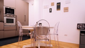 Une cuisine moderne dotée d’appareils électroménagers intégrés, une table à manger avec des chaises et des œuvres d’art murales inspirantes.