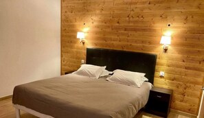 Ein ordentlich bezogenes Bett mit Kopfteil, zwei Nachttischlampen und einem kleinen Nachttisch.