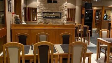 A restaurant with wooden tables and chairs, a stone wall, and a bar area.