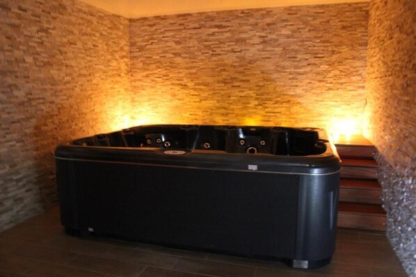 A spa room with a stone wall, a black massage chair, and a wooden bench.