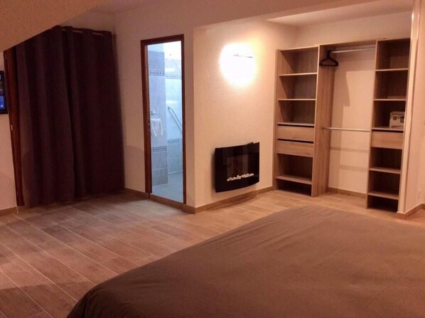Un dormitorio con cama, televisor, armario y puerta corredera.