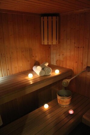 Una sauna de madera con bancos, toallas y velas.