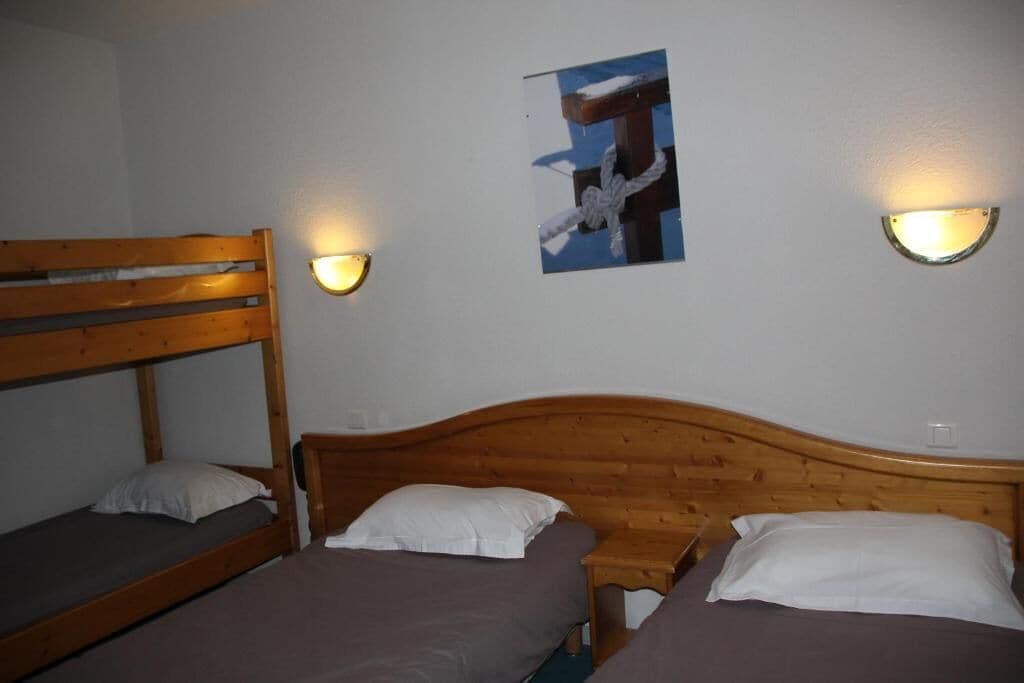 Una habitación con literas y dos mesitas de noche, cada una con una lámpara de pared.