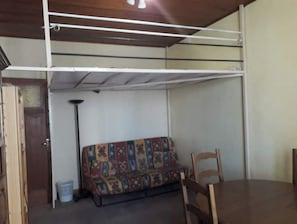 A room with a sofa, a dining table, and a ceiling fan.