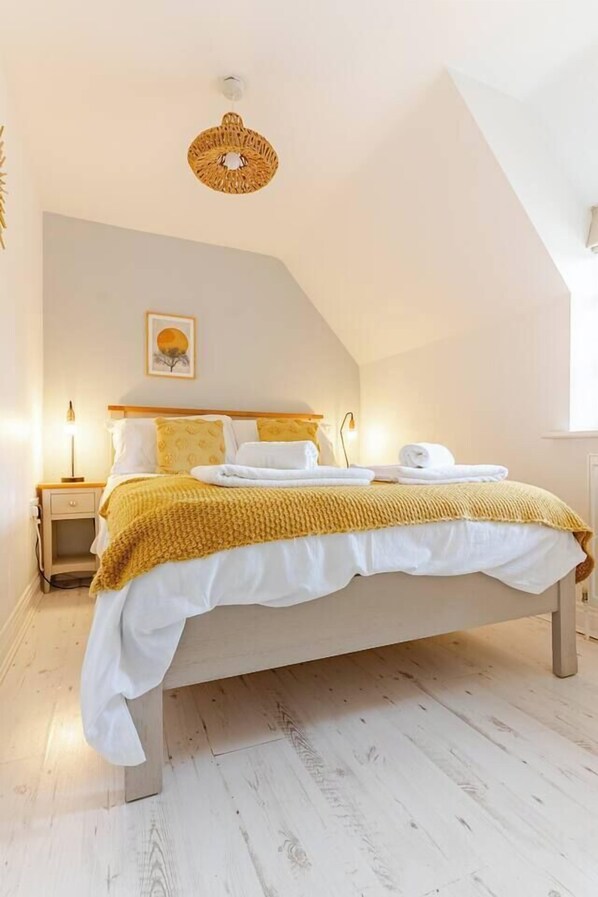 A bedroom with a bed, bedside tables, a wall-mounted lamp, and a ceiling light fixture.