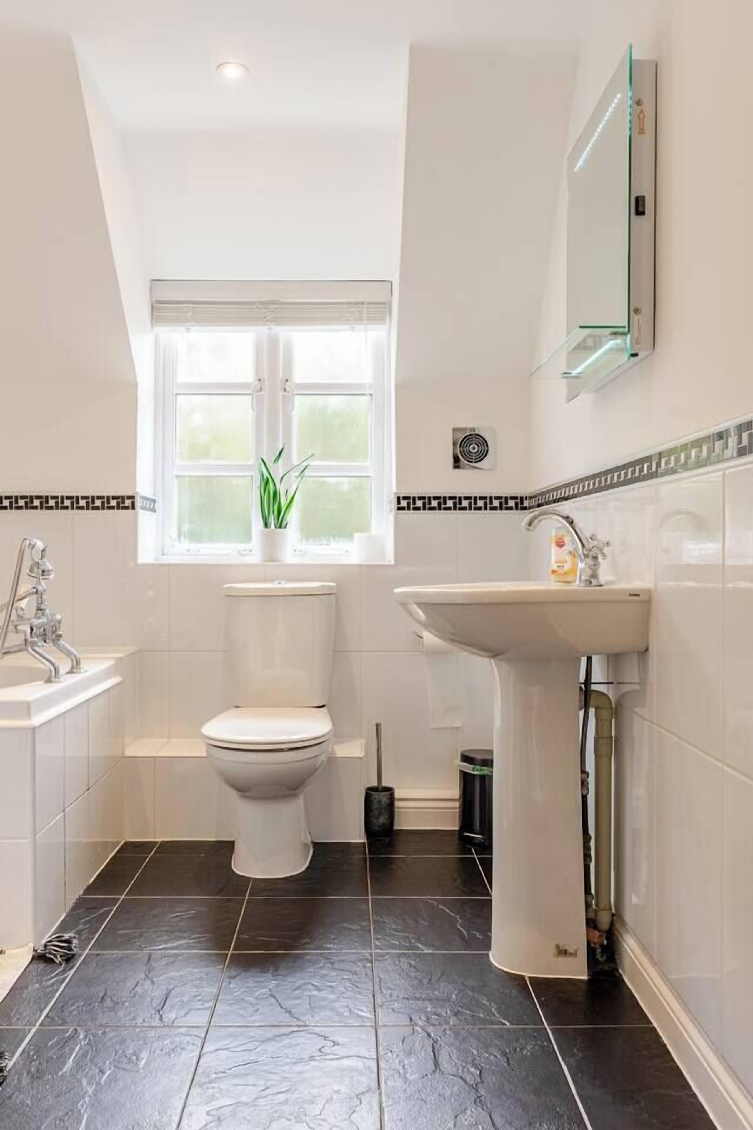 A modern bathroom with a toilet, sink, and window.