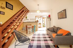A living room with a staircase, a dining area, and a kitchen.