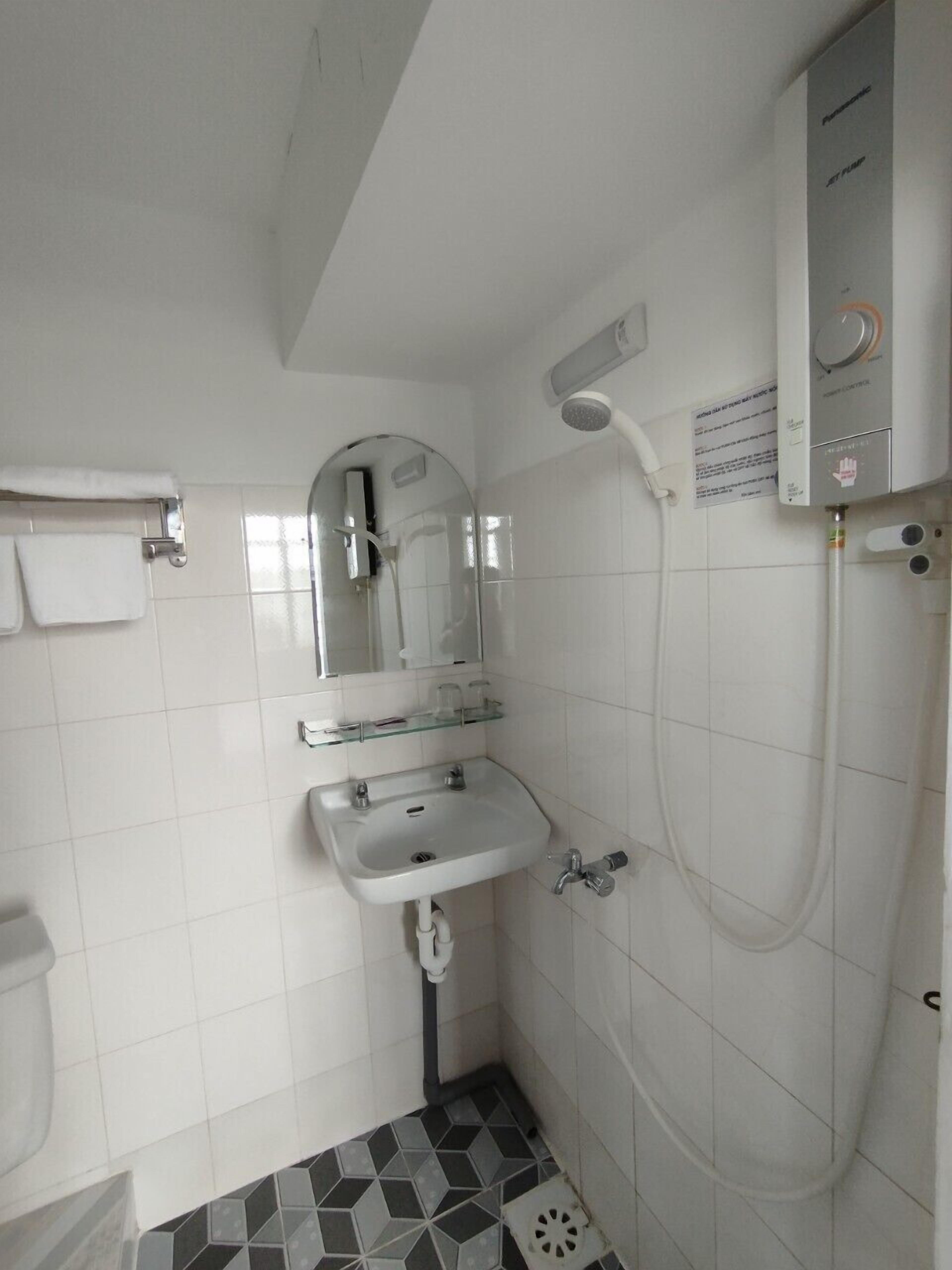 A small bathroom with a white sink, a mirror, and a shower.
