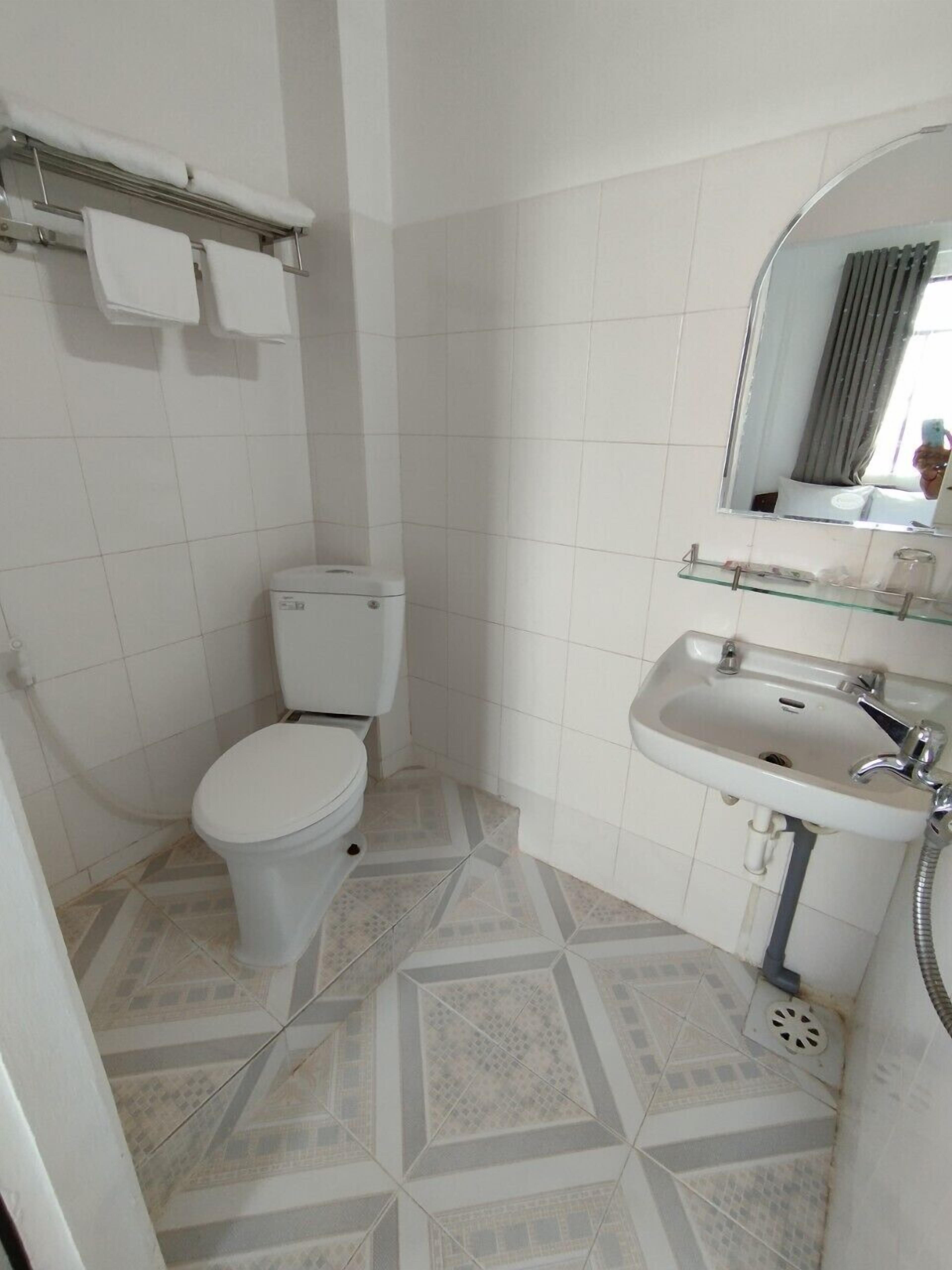 A bathroom with a toilet, sink, and mirror.