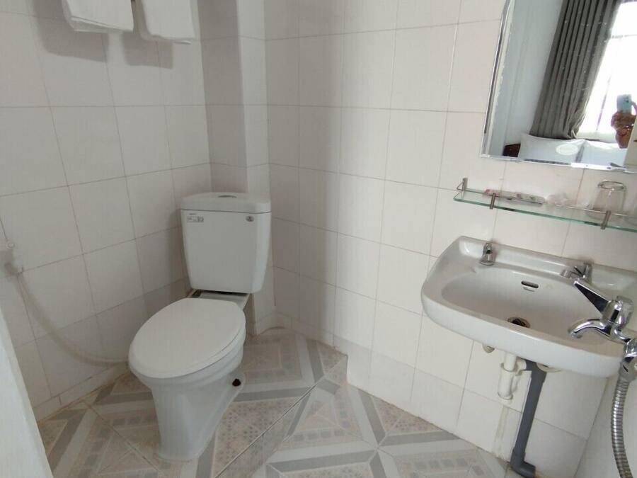 A bathroom with a toilet, sink, and mirror.