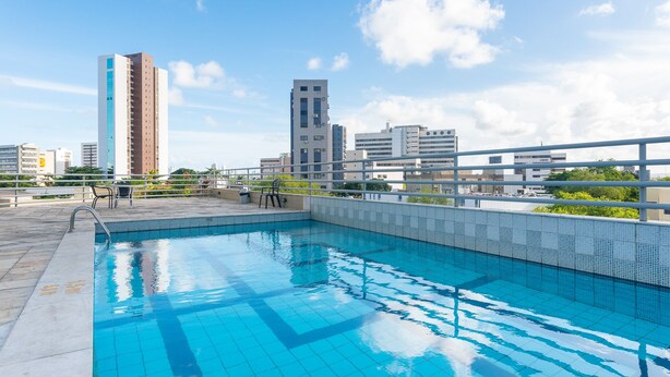 A rooftop swimming pool with a cityscape view, surrounded by a metal railing and a tiled deck. - Flat na Ilha do Leite, Recife 1 quarto. Conforto e Excelente localização OTH1603 (Recife)
