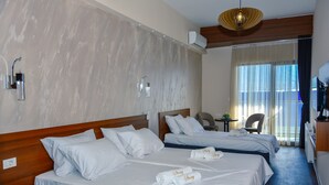 A hotel room with two beds, a wooden headboard, a small table, a chair, and a large window with curtains. - Hotel Story (Skopje)