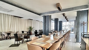 A modern conference room with a long table, comfortable chairs, and a view of the outdoors. - Hotel Story (Skopje)