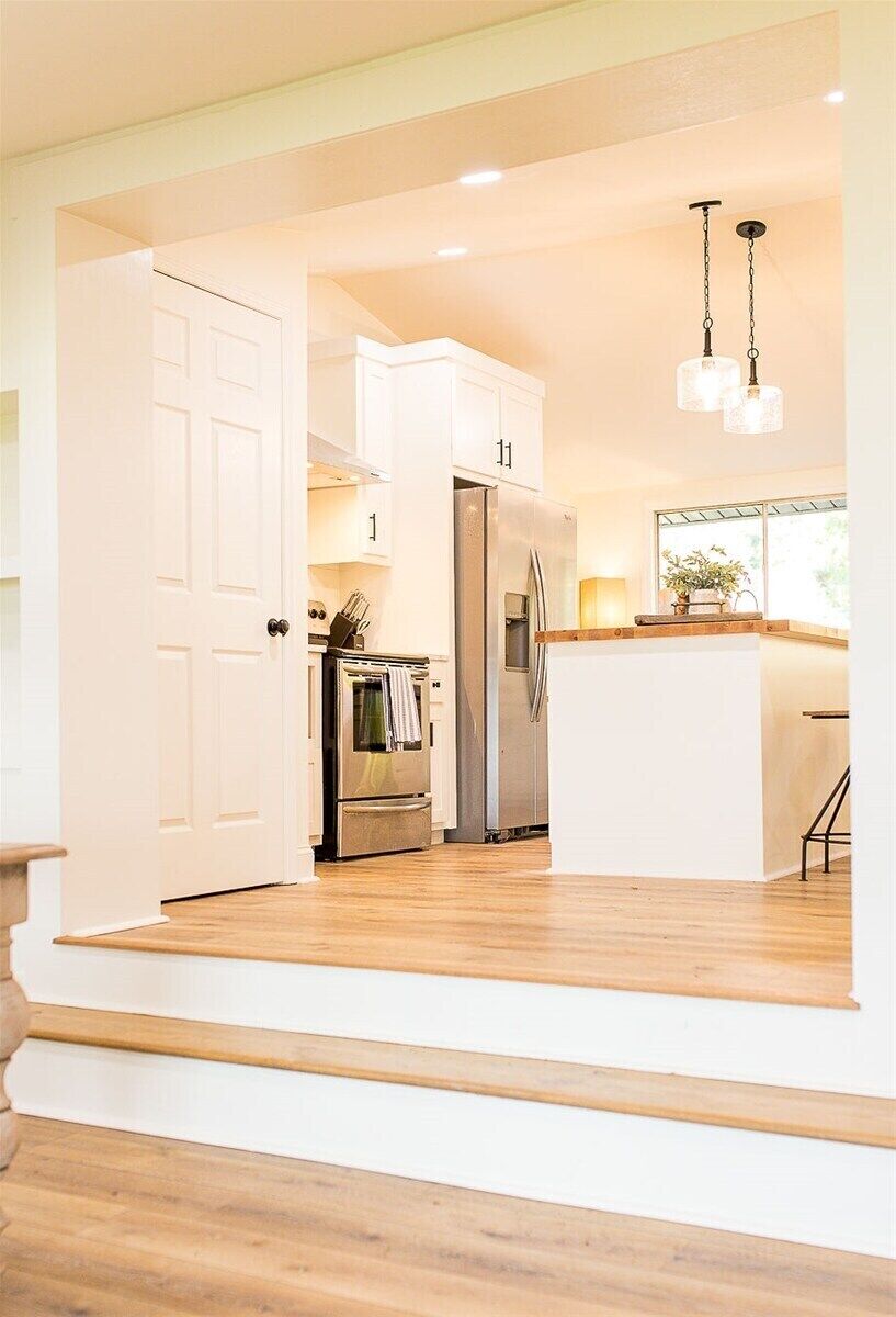 A modern kitchen with white cabinetry, stainless steel appliances, and a wooden island.