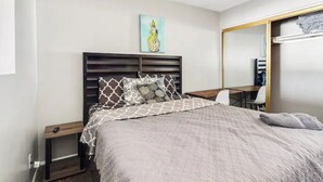 A bedroom with a bed, a nightstand, a desk, a chair, a mirror, and a painting on the wall. - Historic Scottsdale Home with Modern design (Scottsdale)