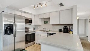 A modern kitchen with stainless steel appliances, white cabinetry, and a central island. - Historic Scottsdale Home with Modern design (Scottsdale)