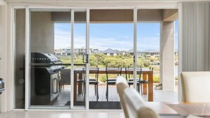 Ein Balkon mit Grill, Esstisch und Stühlen.