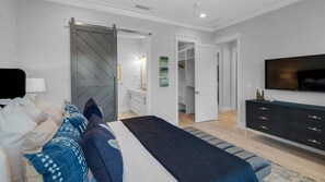 Une chambre à coucher moderne, équipée d’un lit, d’une télévision, d’une armoire et d’un dressing.