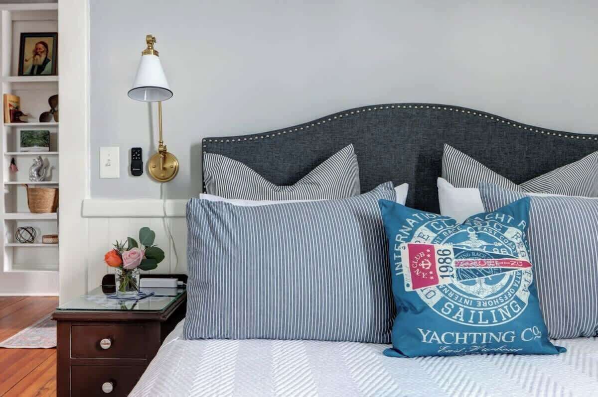Un lit bien fait, avec une literie à rayures et un coussin décoratif sur le thème de la navigation à la voile.