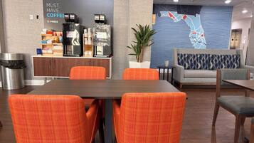 A modern hotel lobby with a coffee bar, seating area, and a map on the wall.