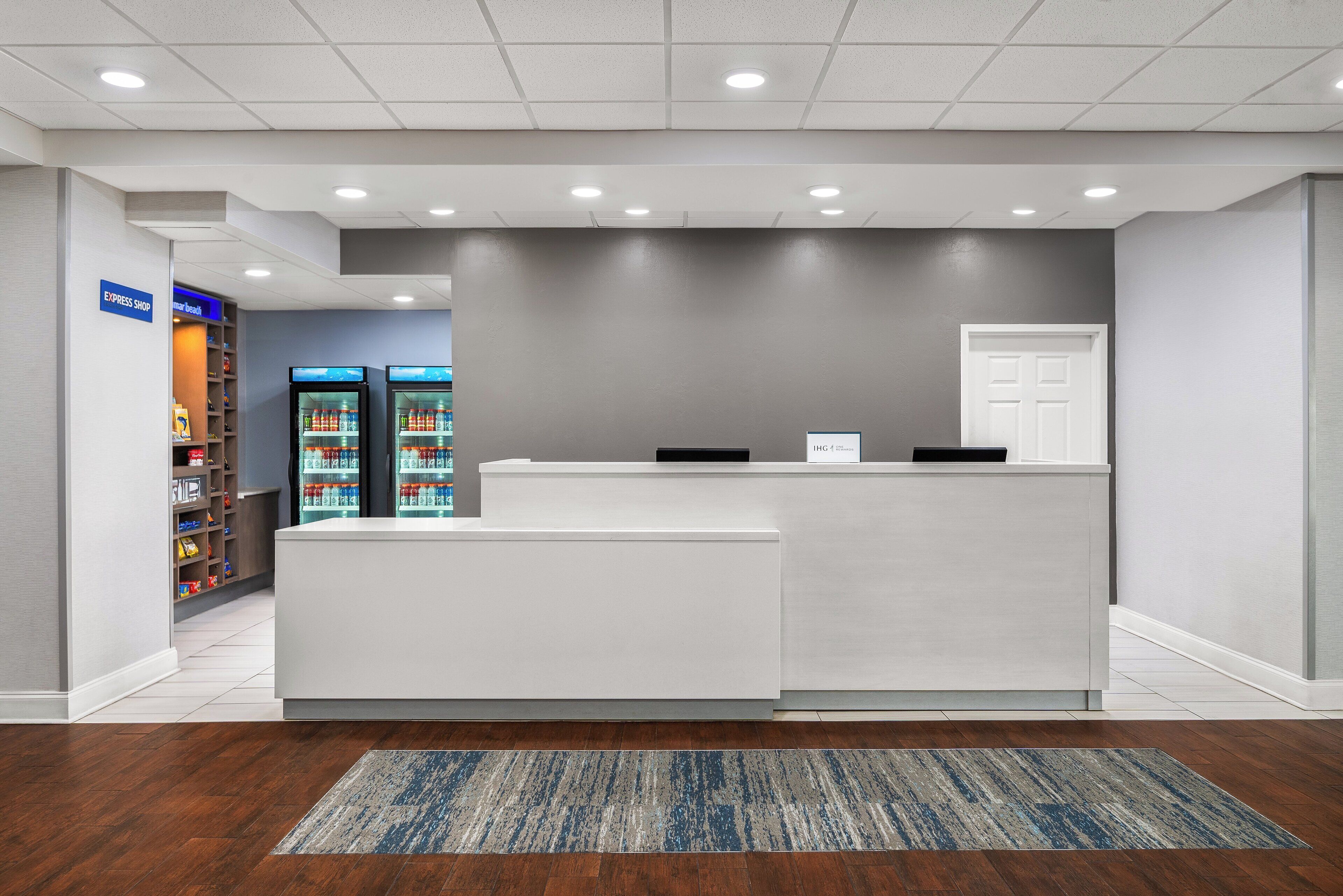 A reception area with a white reception desk, a blue sign indicating an express shop, and a refrigerator stocked with beverages.