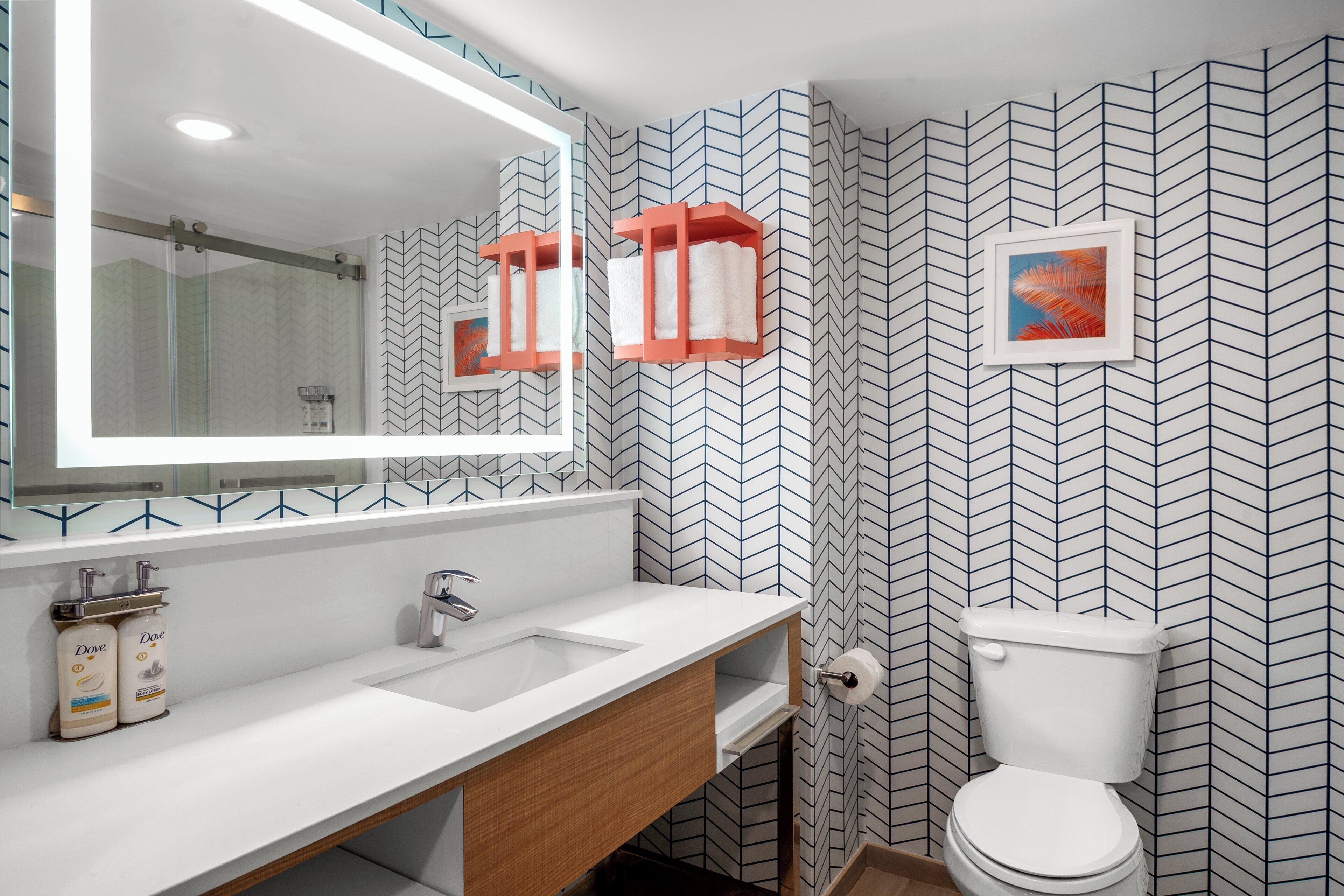 A modern bathroom with a white sink, wooden vanity, and a large mirror.