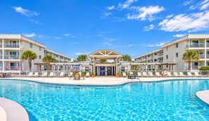 A hotel with a swimming pool, multiple balconies, and a covered area with lounge chairs. - Beachfront Resort Escape | 6 Pools + Indoor Pool | Sleeps 6 (Gulf Shores)