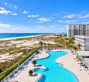Un resort con piscina, acceso a la playa y un edificio de varios pisos.