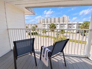 A balcony with two chairs and a view of a parking lot and buildings. - Beachfront Resort Escape | 6 Pools + Indoor Pool | Sleeps 6 (Gulf Shores)