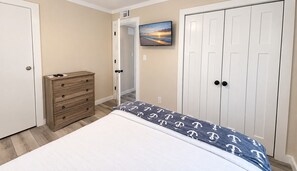 A bedroom with a bed, a dresser, a closet, and a door leading to a bathroom. - Beachfront Resort Escape | 6 Pools + Indoor Pool | Sleeps 6 (Gulf Shores)
