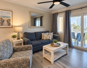 A living room with a sofa, armchair, coffee table, and a ceiling fan. - Beachfront Resort Escape | 6 Pools + Indoor Pool | Sleeps 6 (Gulf Shores)