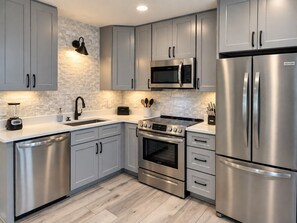A modern kitchen with grey cabinets, stainless steel appliances, a microwave, a stove, and a dishwasher. - Beachfront Resort Escape | 6 Pools + Indoor Pool | Sleeps 6 (Gulf Shores)