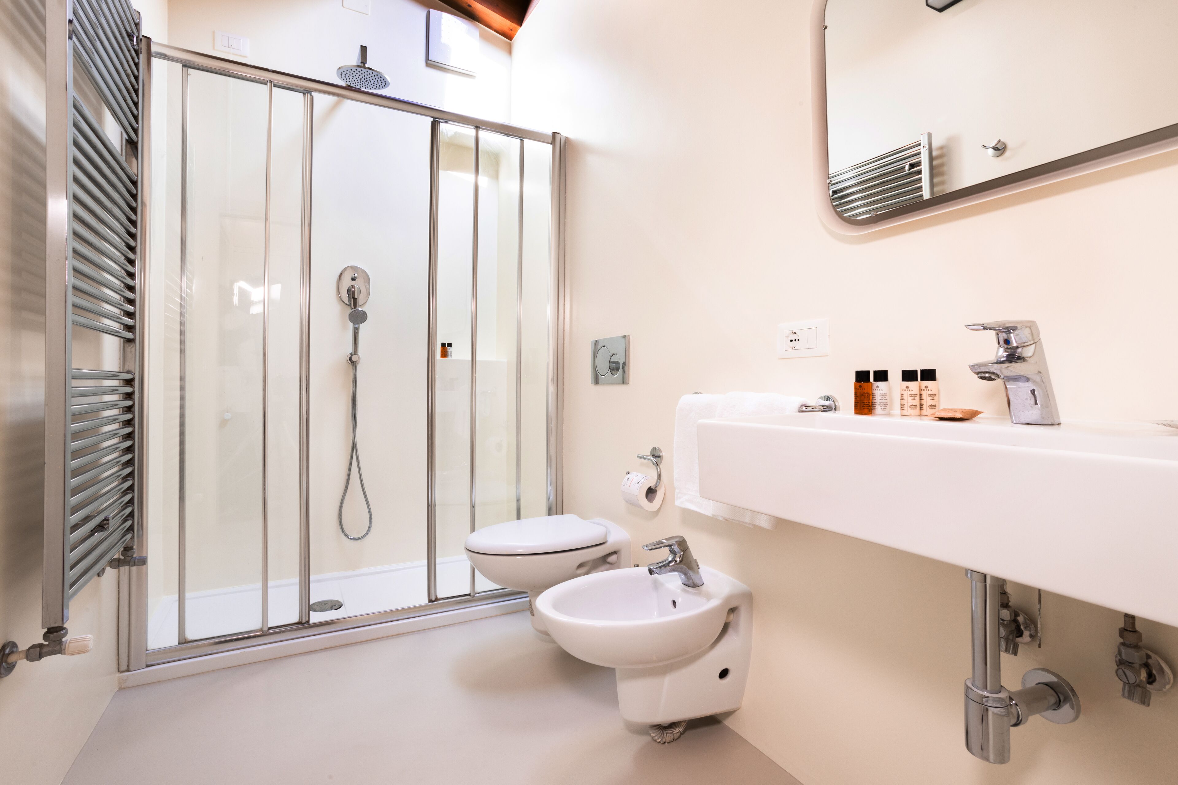 Un baño moderno con ducha de vidrio, lavamanos blanco y bidé.